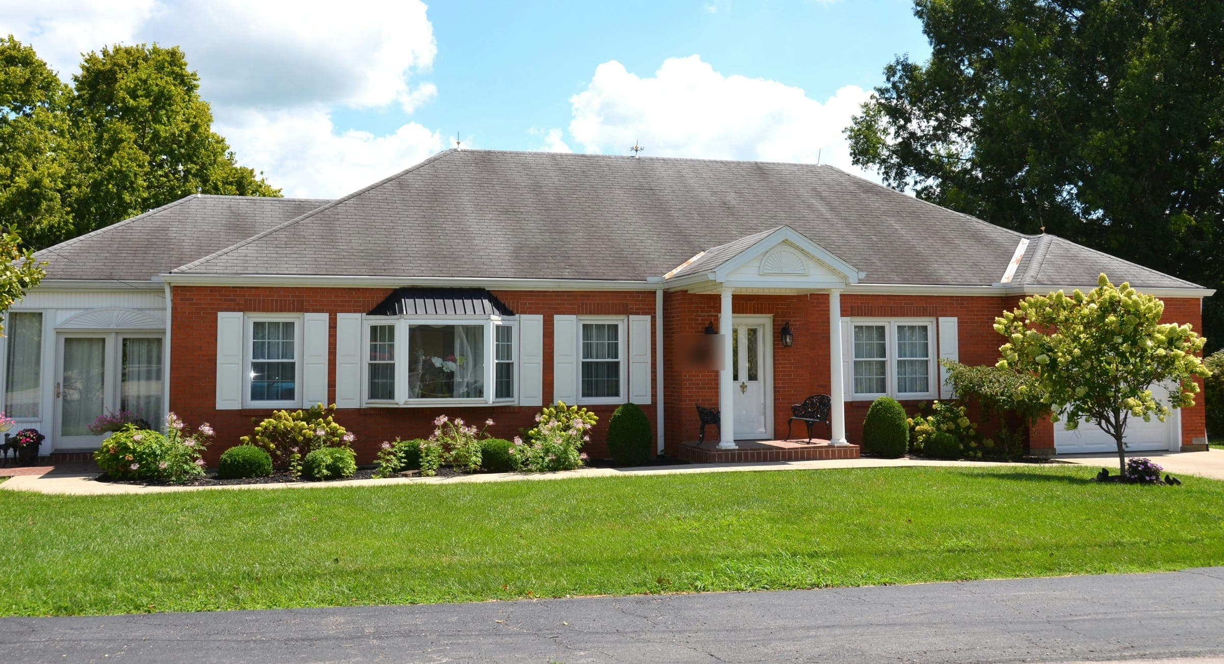 Single-story brick ranch house with white shutters, a small front porch and a wide lawn